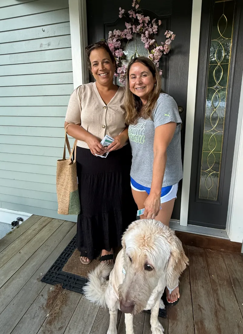 Suzy and a resident with her dog on a front porch