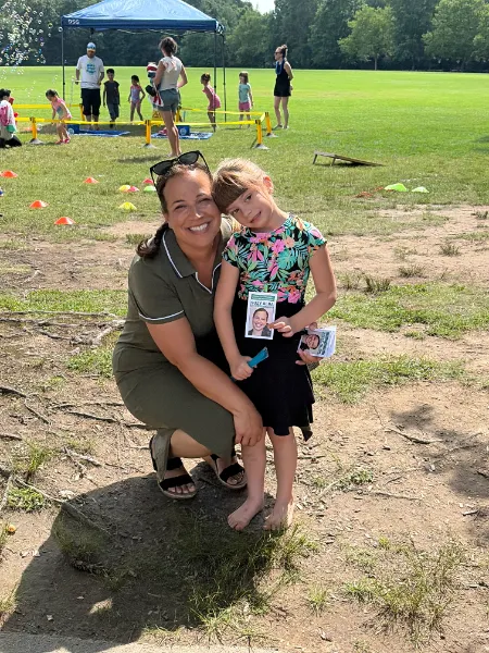 Suzy crouching with a young girl at a community field day
