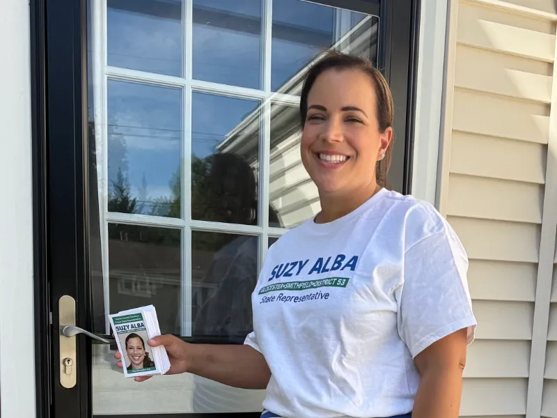 Suzy holding campaign flyers at a resident's front door